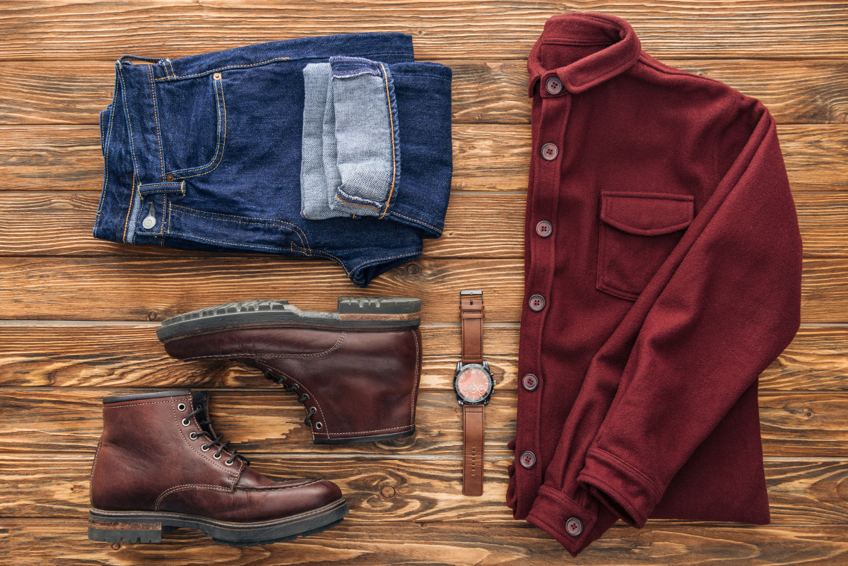 Flat lay with shirt, jeans and brown boots on wooden background